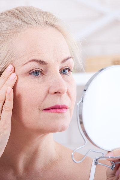 A woman looking at her face in the mirror