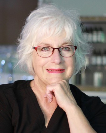 A woman with white hair and glasses is posing for the camera.