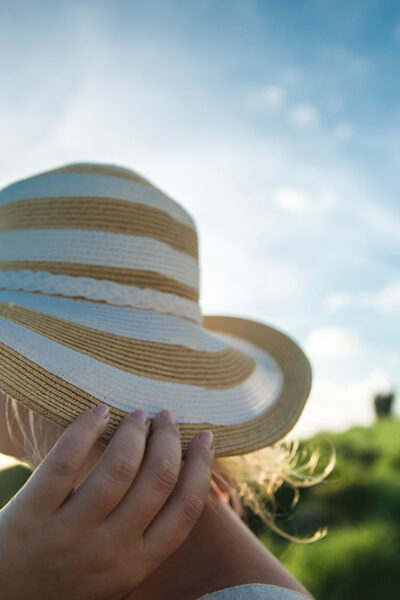 A person holding onto the hat of their head