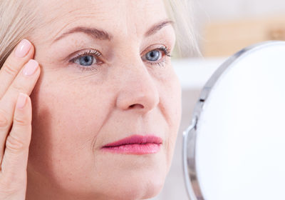 A woman looking at her face in the mirror