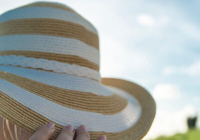 A person holding onto the hat of their head